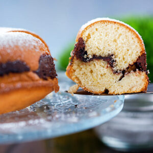 Cake on plate with a slice on a spatula.