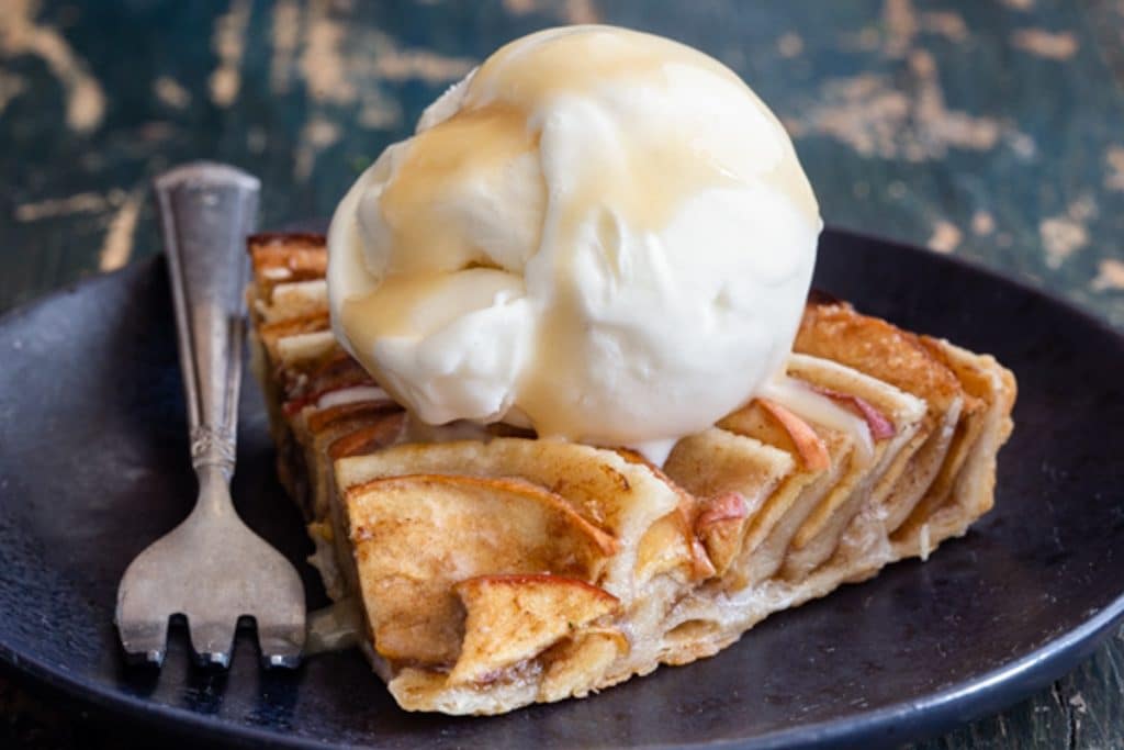 A slice of apple pie with a scoop of ice cream on top.
