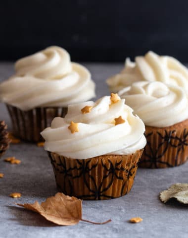 4 pumpkin cupcakes on with small stars on a grey board with 2 leaves