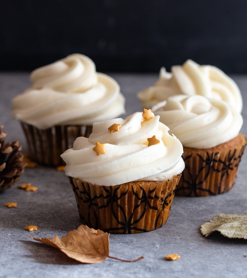 4 pumpkin cupcakes on with small stars on a grey board with 2 leaves