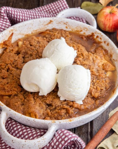 apple crisp in a white pan with 3 scoops of ice cream