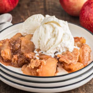 Apple crisp in a plate with ice cream on top.