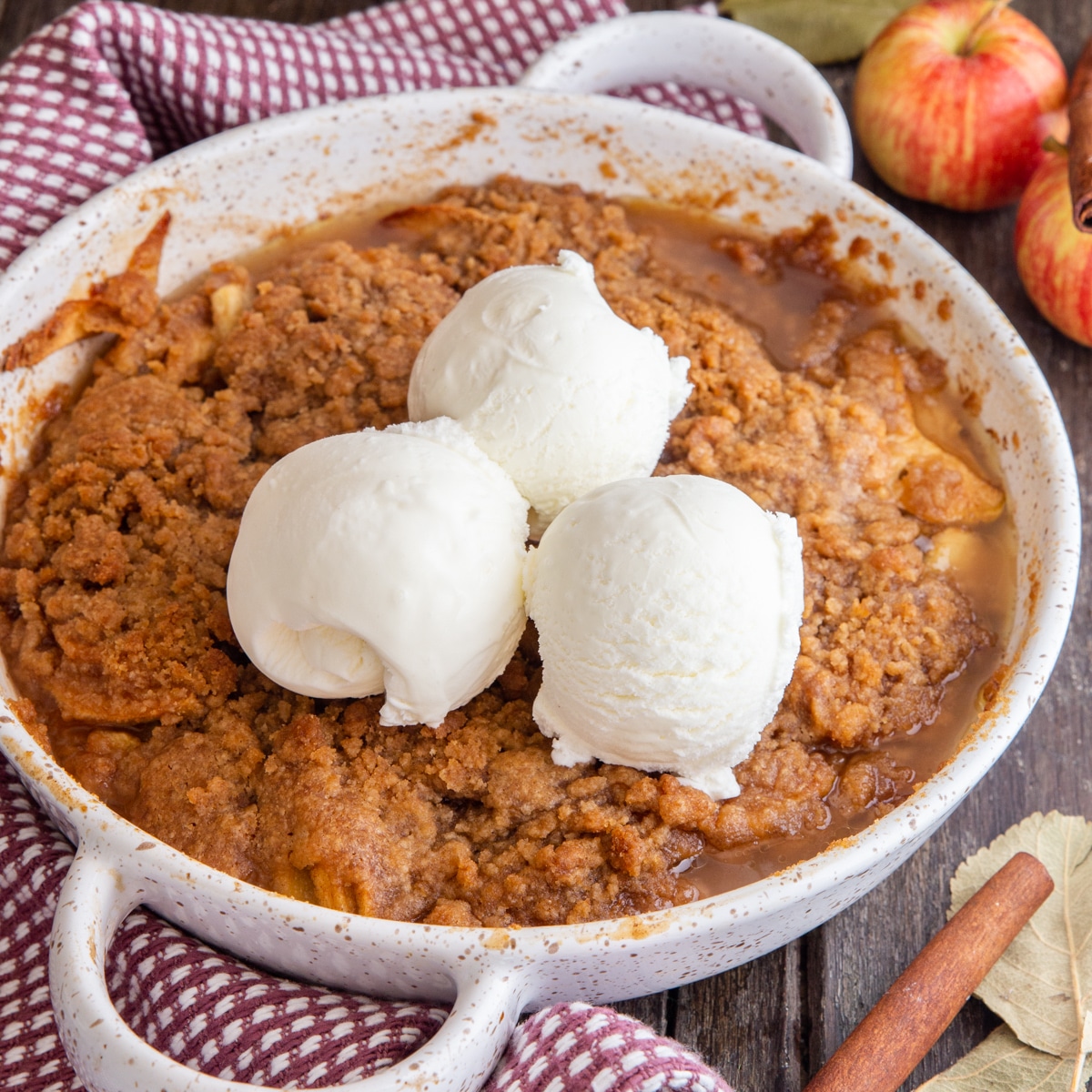 apple crisp in a white pan with 3 scoops of ice cream