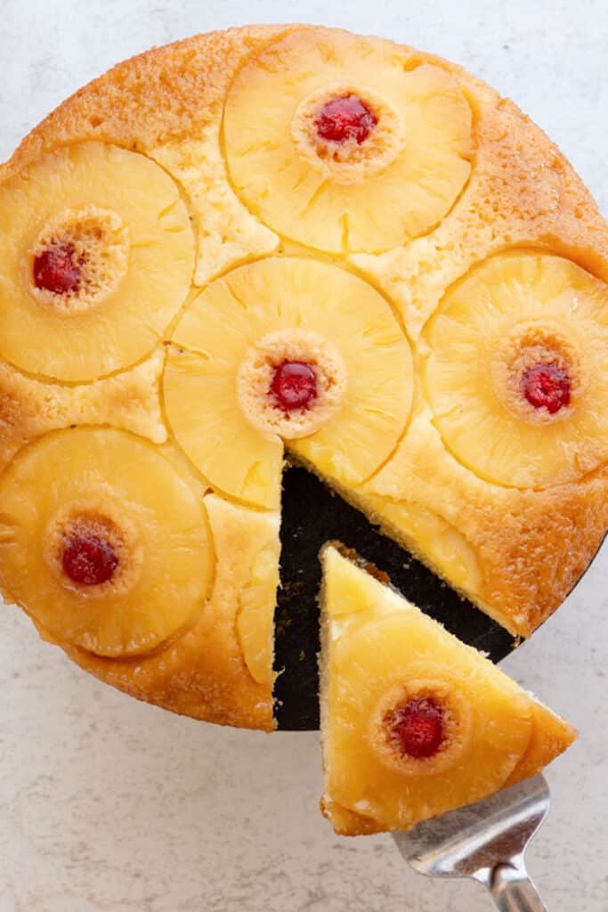 Pineapple cake on a white board with a slice cut.