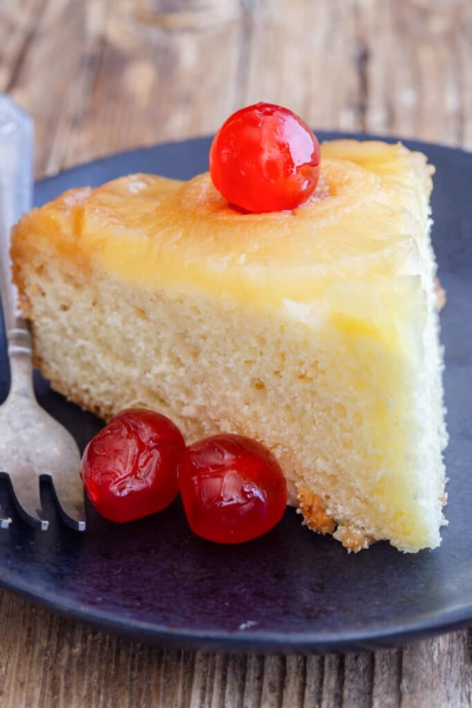 A slice of cake on a black plate.