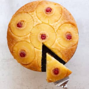 Pineapple cake on a white board with a slice cut.