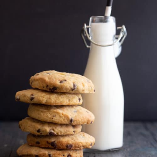 6 pumpkin cookies stacked with a bottle of milk and a straw