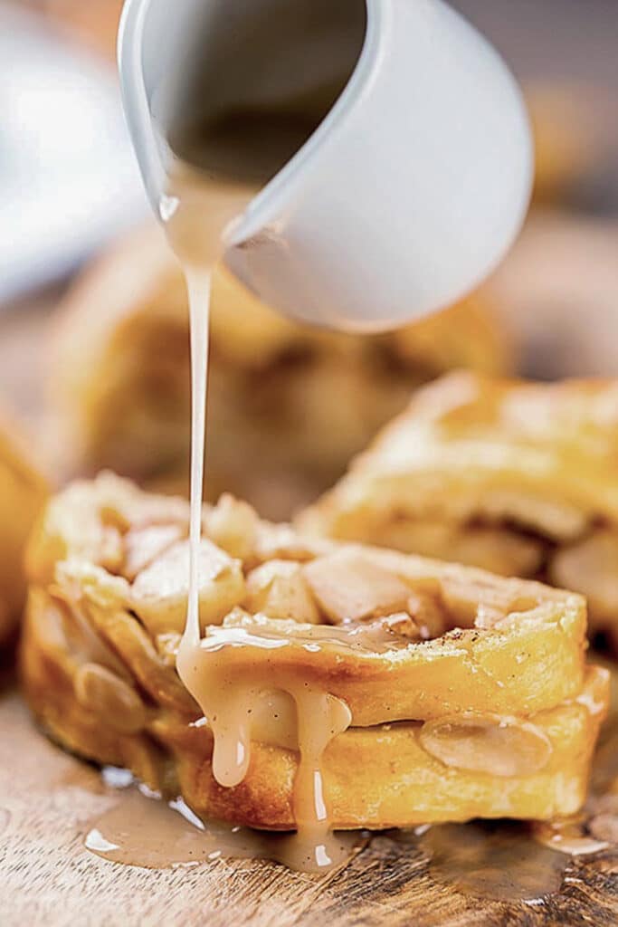Pouring syrup on a slice of strudel.