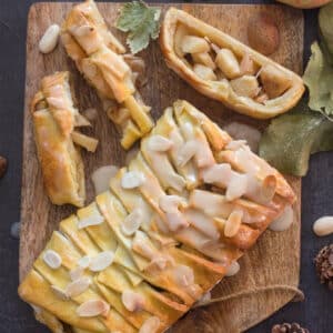Cinnamon apple strudel with three slices cut on a wooden board.