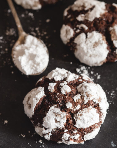 crinkle cookies on a black board with a spoon of powdered sugar