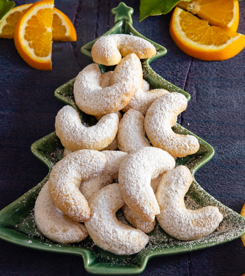 orange crescent cookies on a green tree plate with orange slices