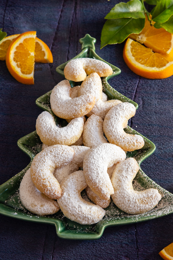 orange crescent cookies on a green tree plate with orange slices