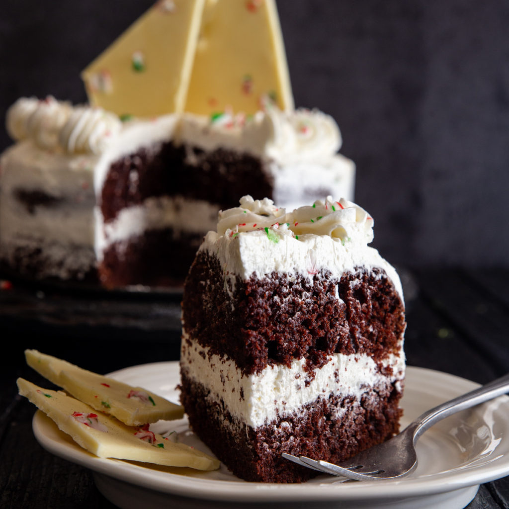 a slice of cake on a white plate with the remaining cake in the background