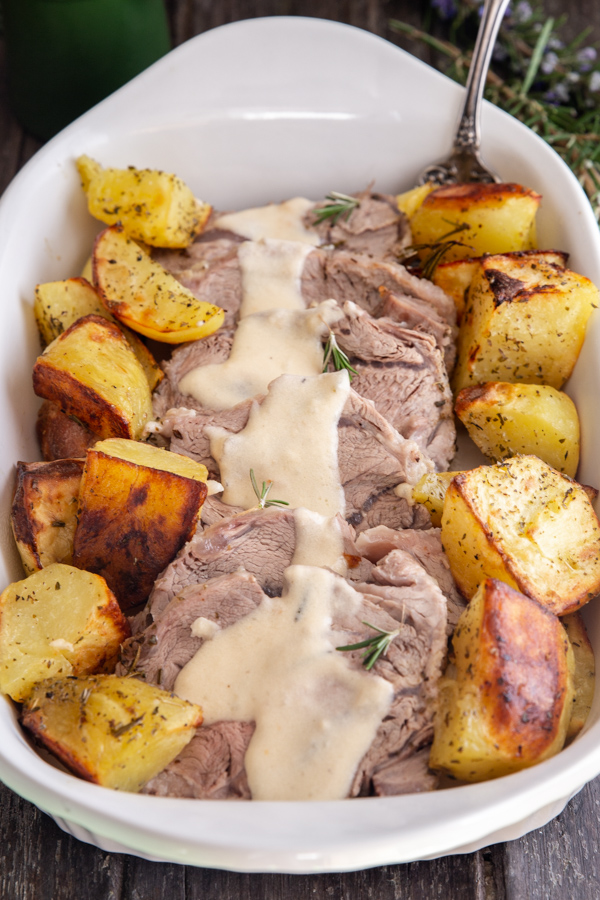 roast in milk with roasted potatoes in a white dish