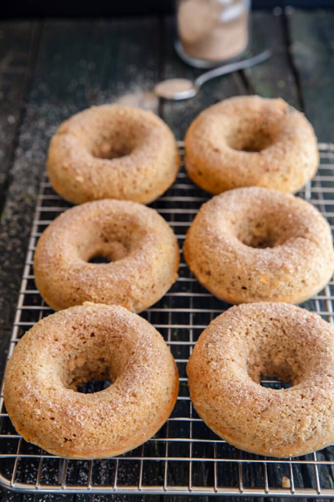 Six baked donuts on a wire rack.