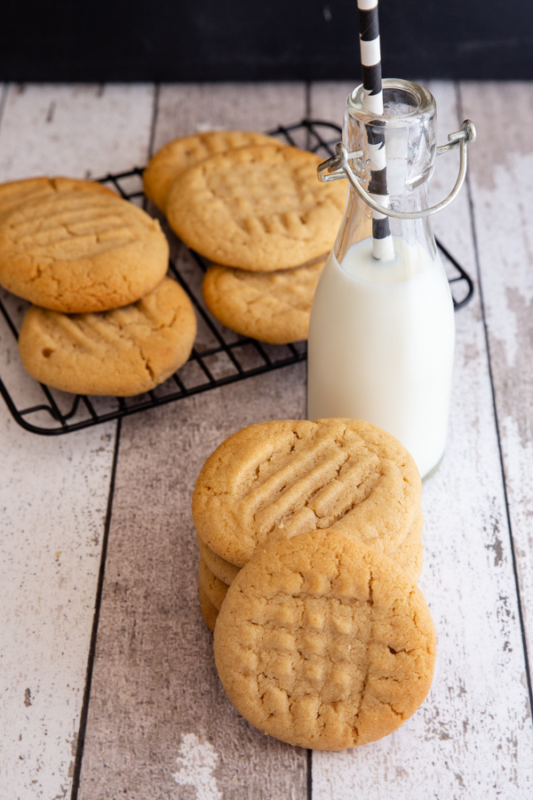 cookies stacked and on a rack with a bottle of milk