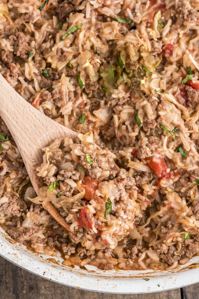 Cabbage roll casserole on a wooden spoon and in the pan.