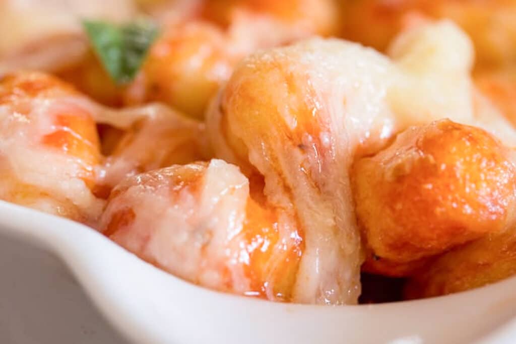 Baked cheesy gnocchi in a white baking dish.