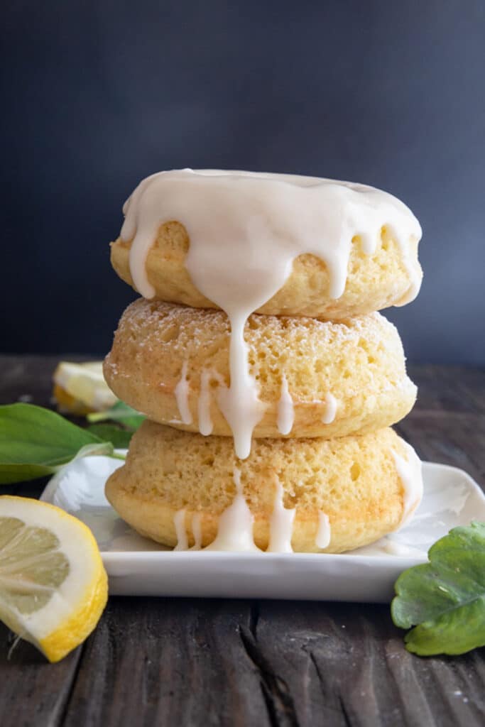 Three donuts stacked on a white plate.