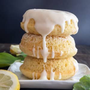 Three donuts stacked on a white plate.