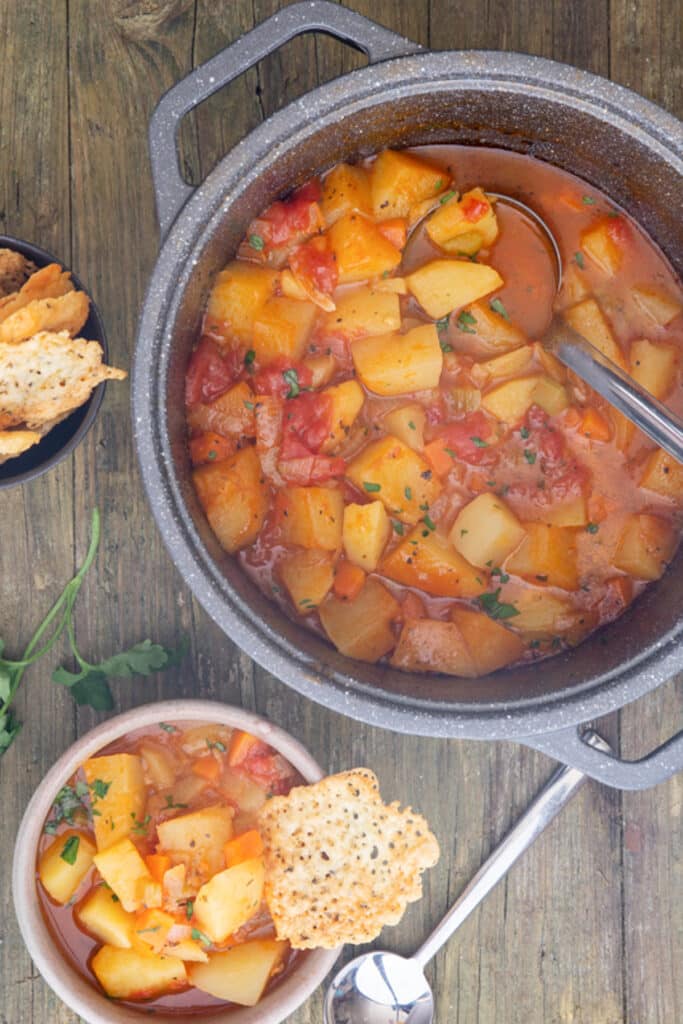 Soup in a pot and some in a grey bowl.