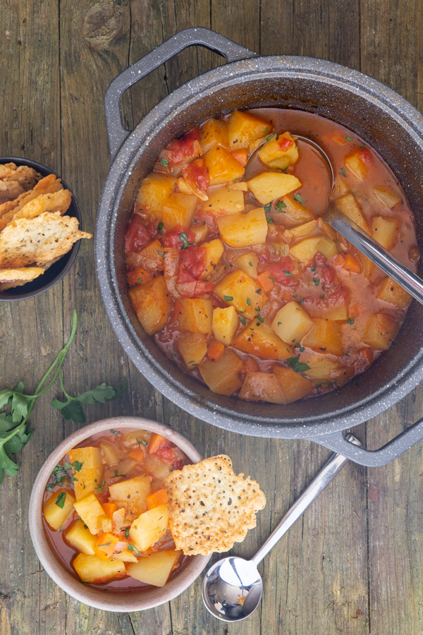 soup in the pot and some in a bowl with a cheese crisp