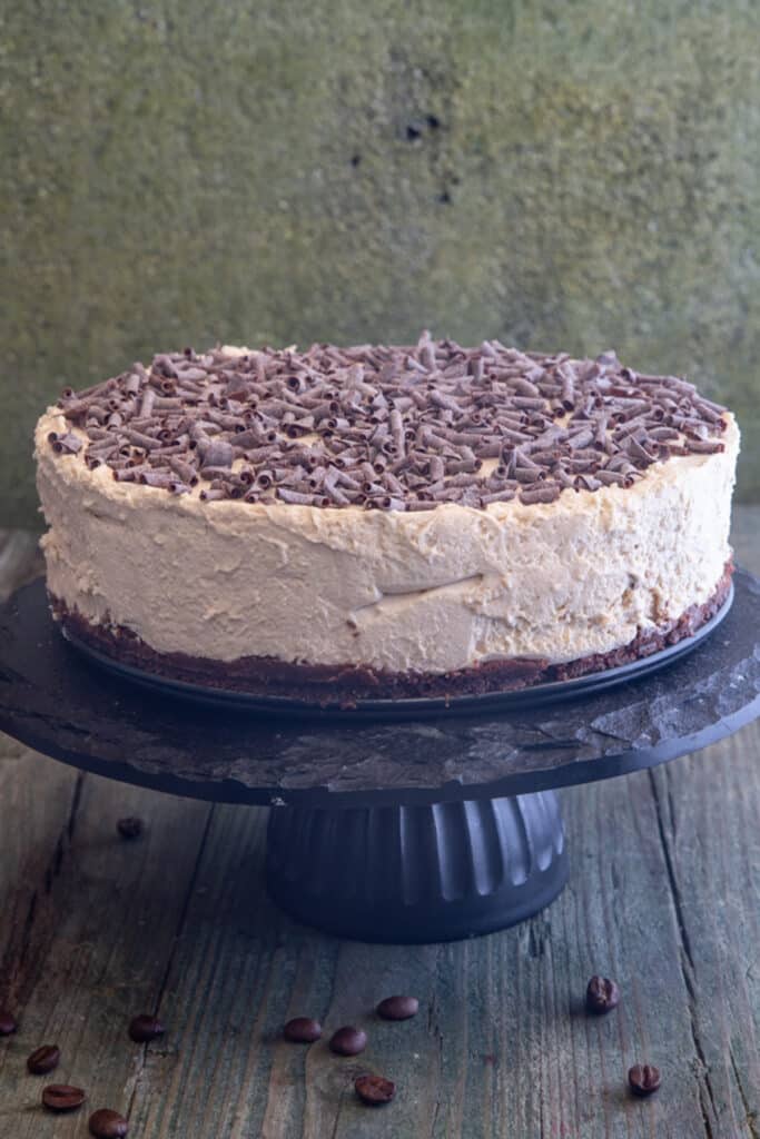 Cappuccino cheesecake on a black cake stand.