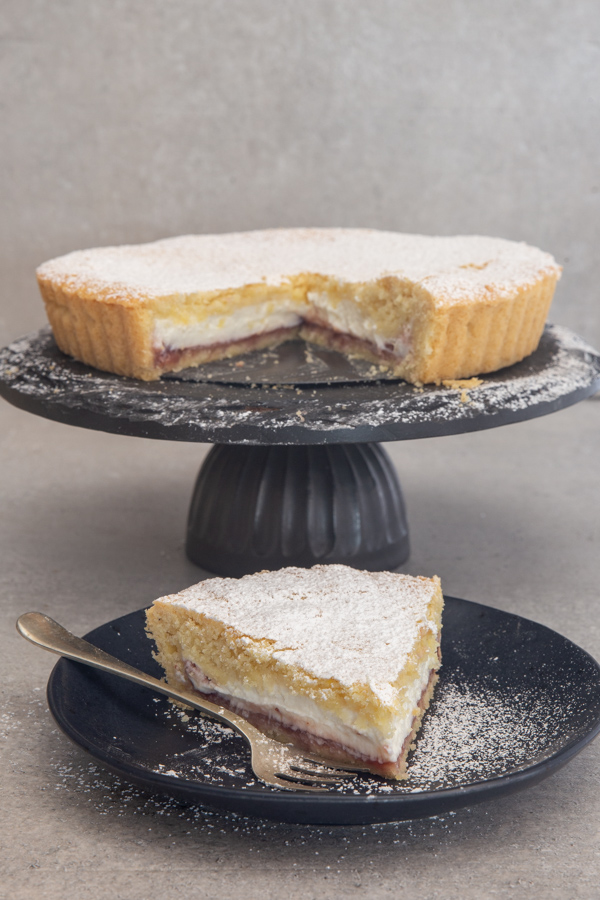 cake on a black stand with a slice on a black plate