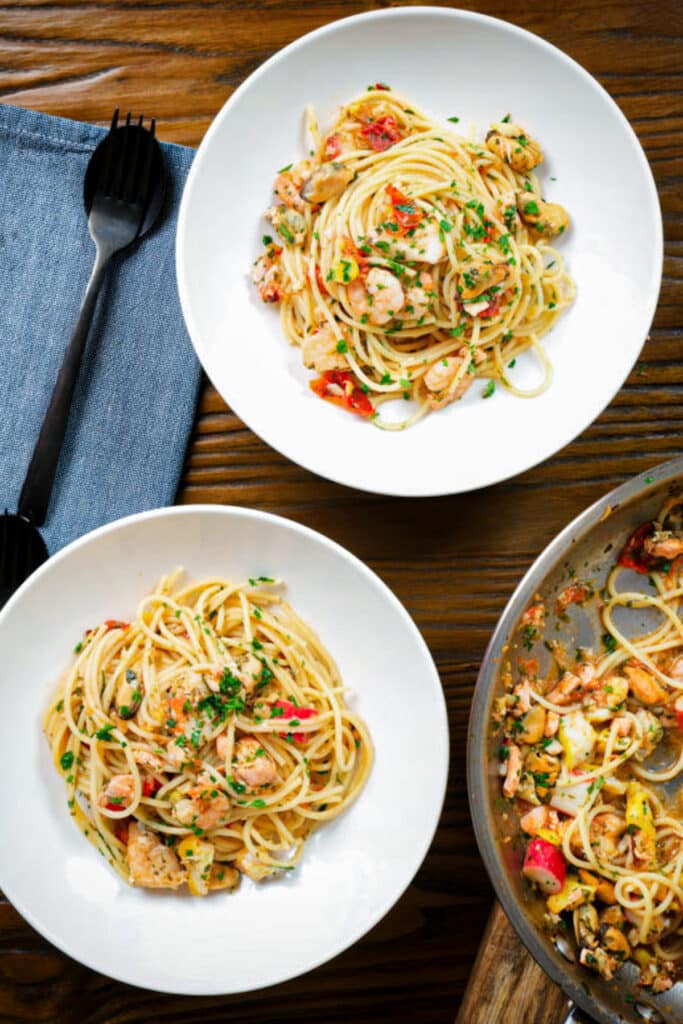 Italian seafood pasta in 2 bowls and some in the pan.