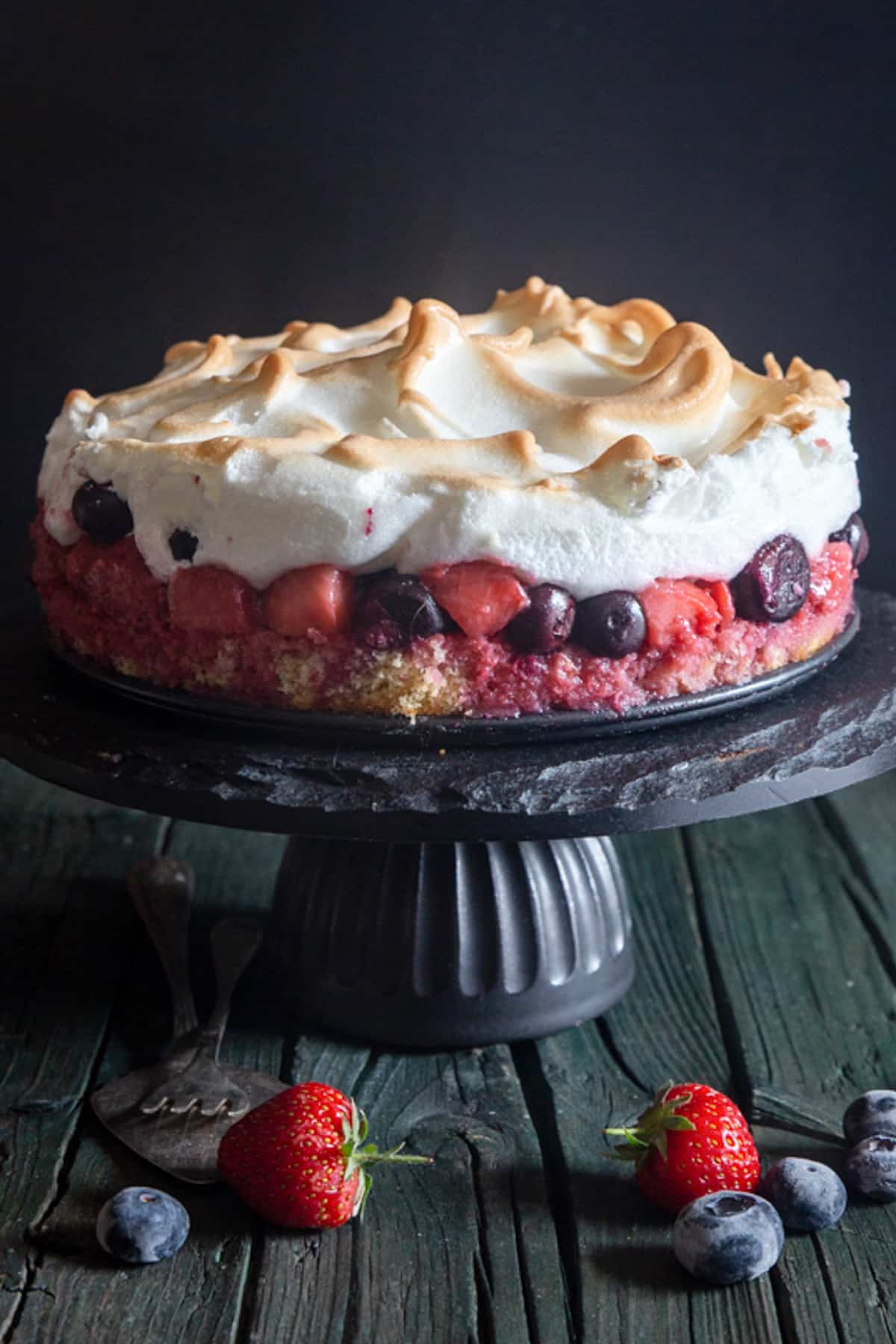 Meringue cake on a black cake stand.