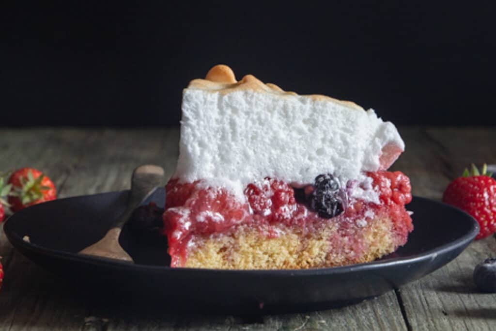 A slice of cake on a black plate.