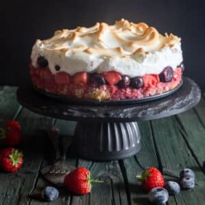 Meringue cake on a black cake stand.