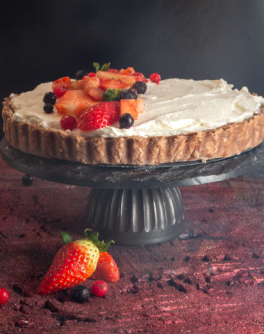 strawberry pie on a black cake stand on a red board.