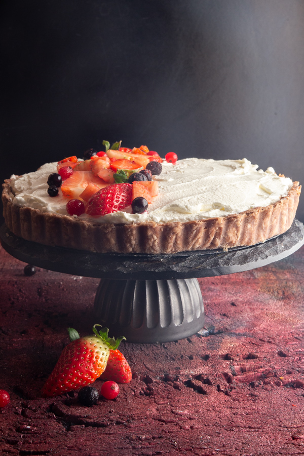 strawberry pie on a black cake stand on a red board.