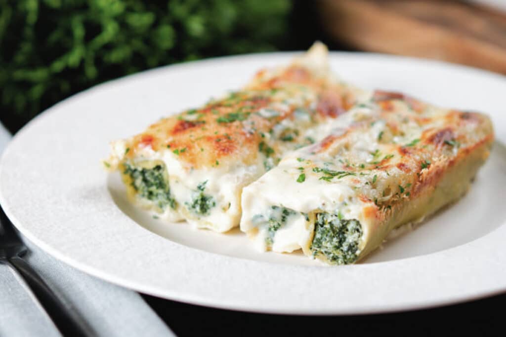 Two cannelloni on a white plate.