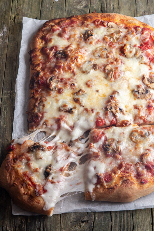 pizza on parchment paper with a slice cut.