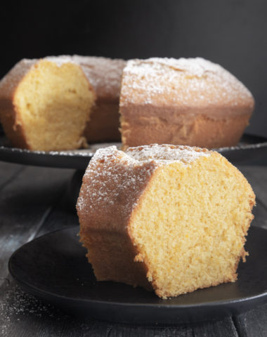 Bundt cake on a black stand with a slice cut.