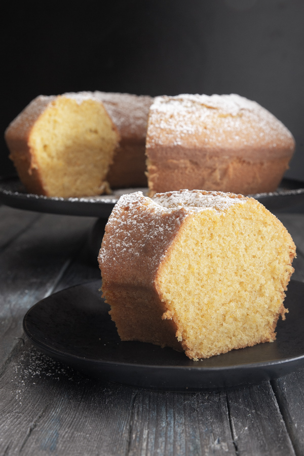 bundt cake on a black stand with a slice cut.