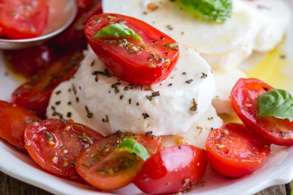 Slices of mozzarella with tomatoes on top.