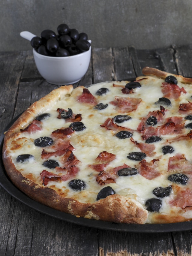 Pizza baked with olives in a white bowl.