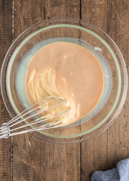 Mixing the baileys and sweetened condensed milk in a glass bowl.
