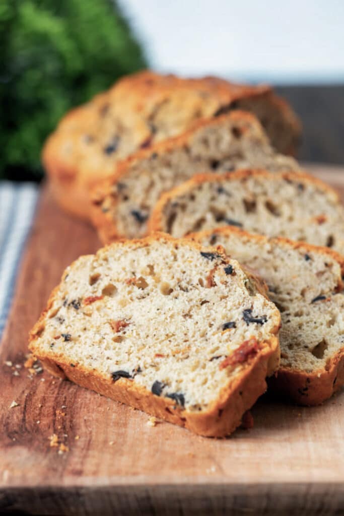 Bread with three slices cut on a wooden board.