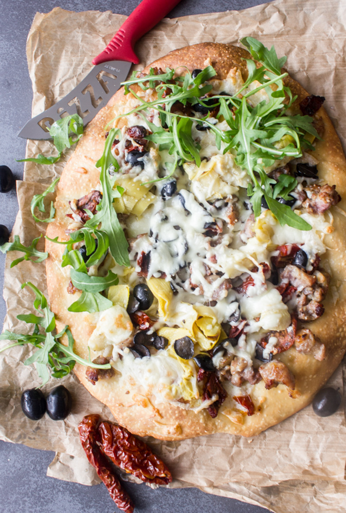 Sausage & arugula pizza on a brown paper.