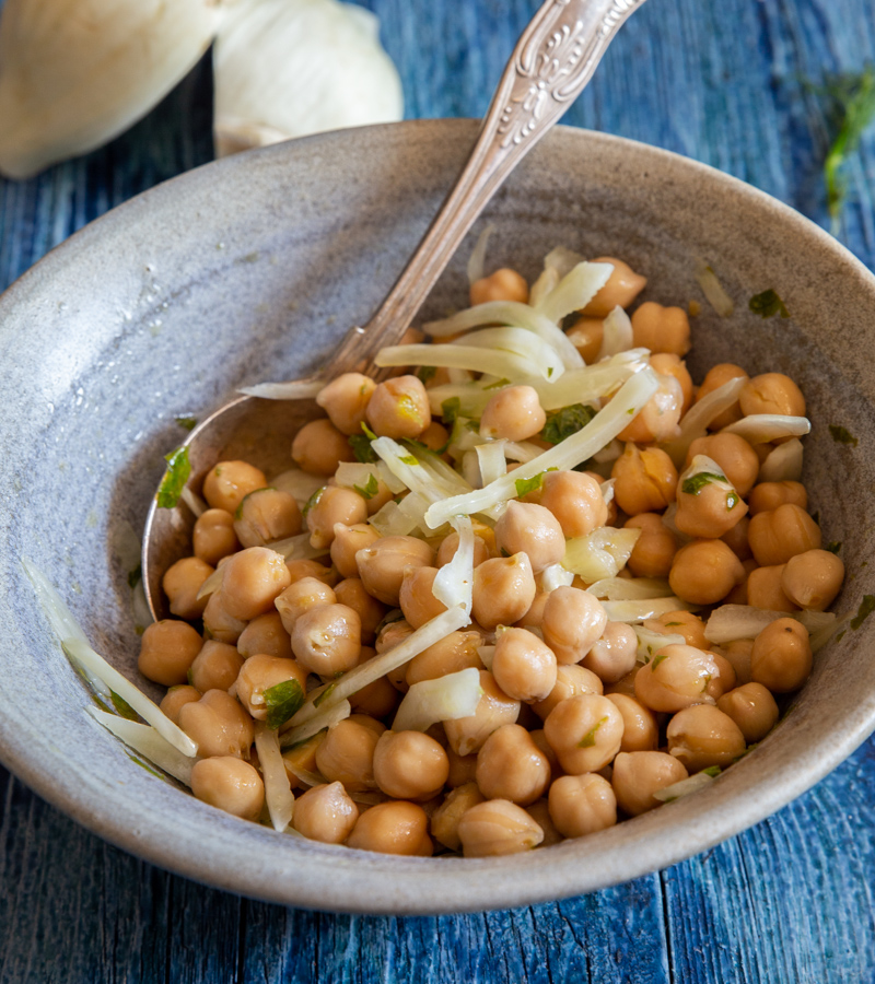 Chickpeas salad in a grey bowl with a silver spoon.