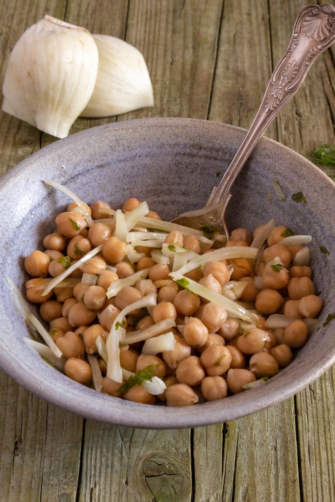 Chickpeas salad in a grey bowl with a silver spoon.