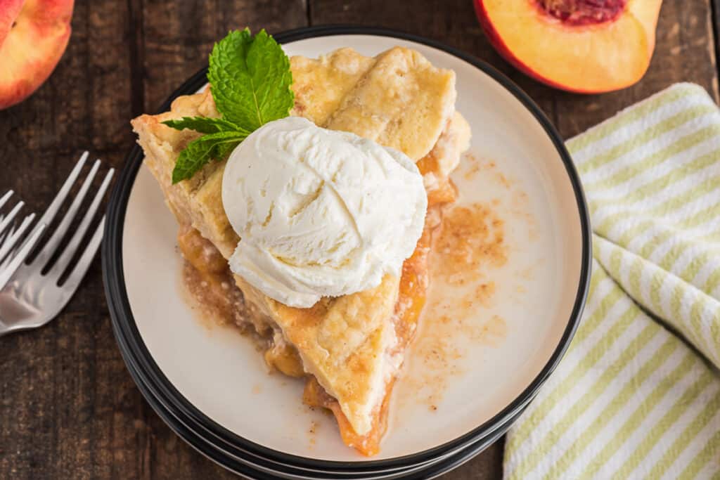 A slice of pie on a white plate with a scoop of ice cream.