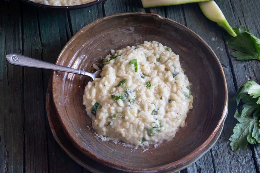 Zucchini risotto in a brown plate.