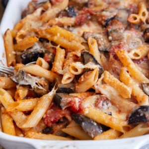 Sicilian pasta with some on a spoon in a white baking dish.