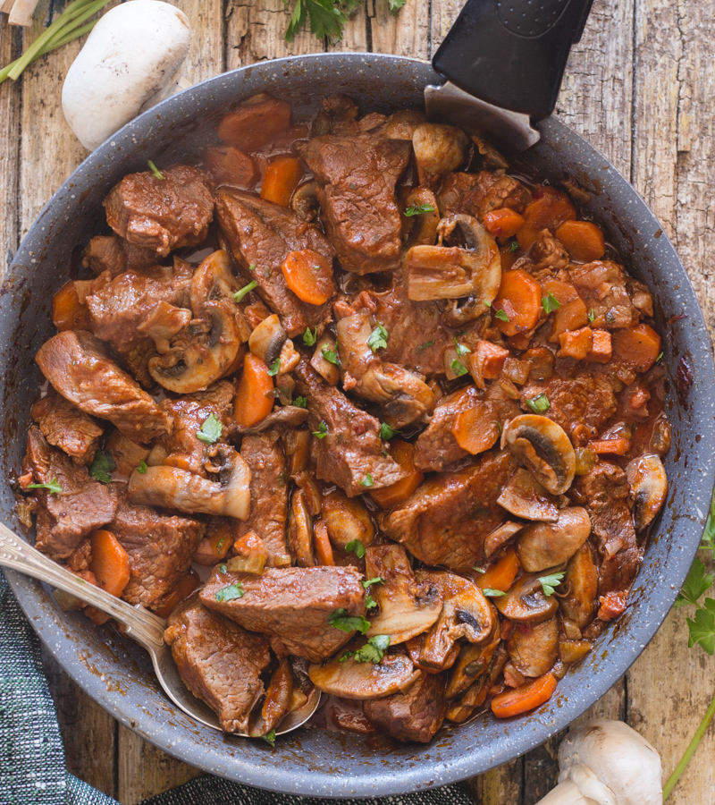 Mushroom & beef in a pan with a silver spoon.