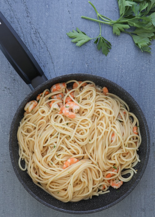 Adding the pasta to the shrimp.